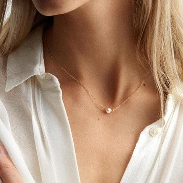 Colar AURA dourado com pérola sintética usado ao pescoço