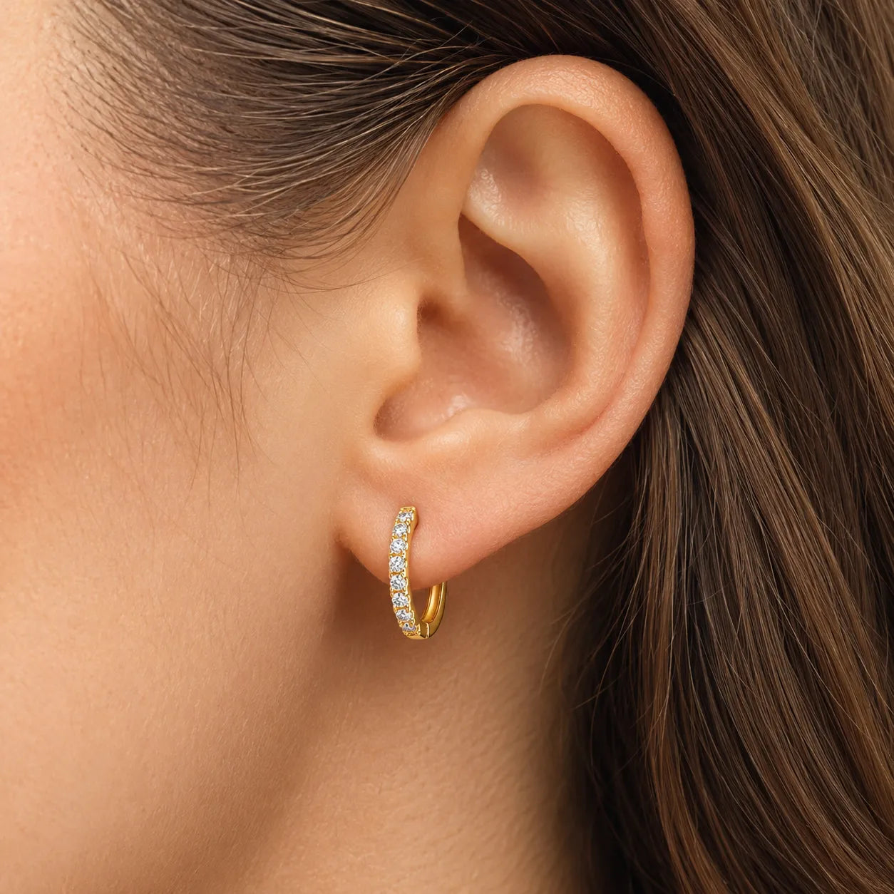 Brinco de argola dourado com zircónia cúbica em uso na orelha