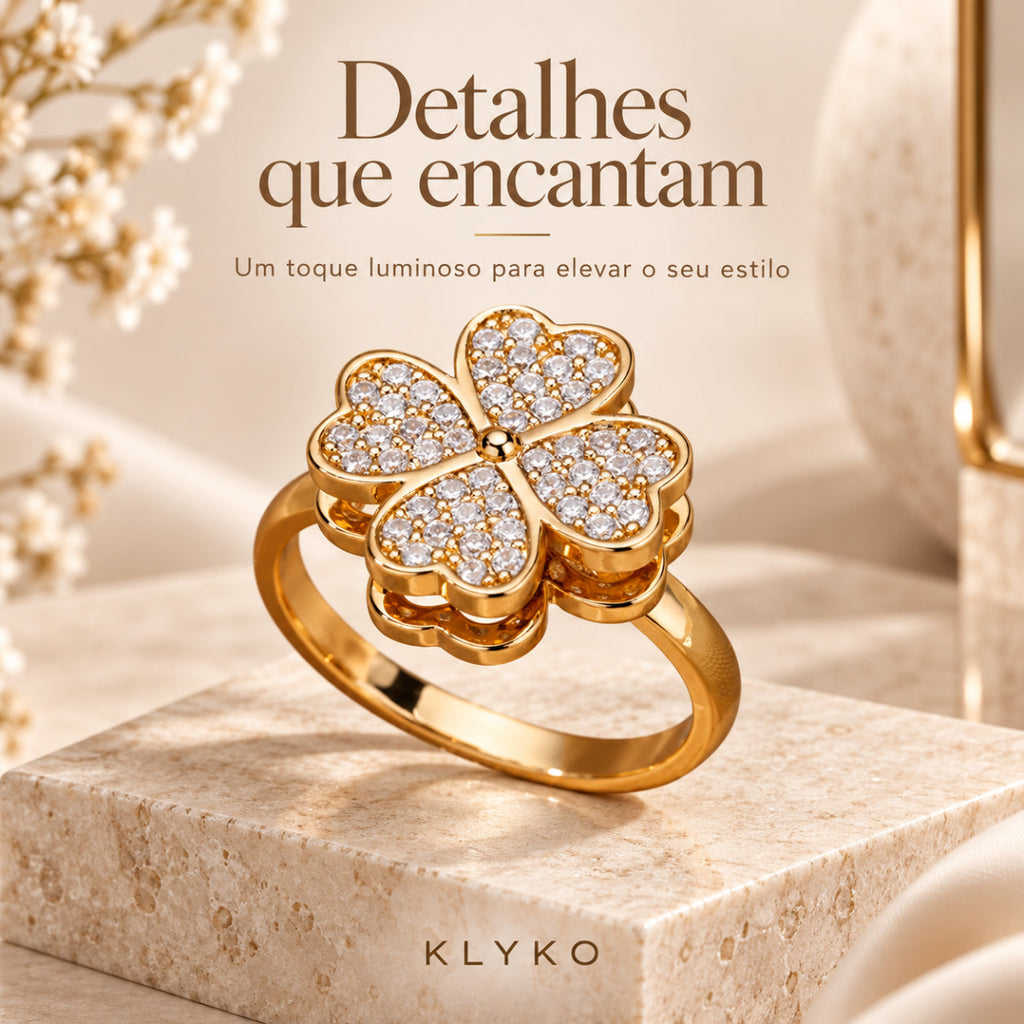 Anel HOPE com acabamento dourado e detalhes brilhantes em destaque num cenário bege