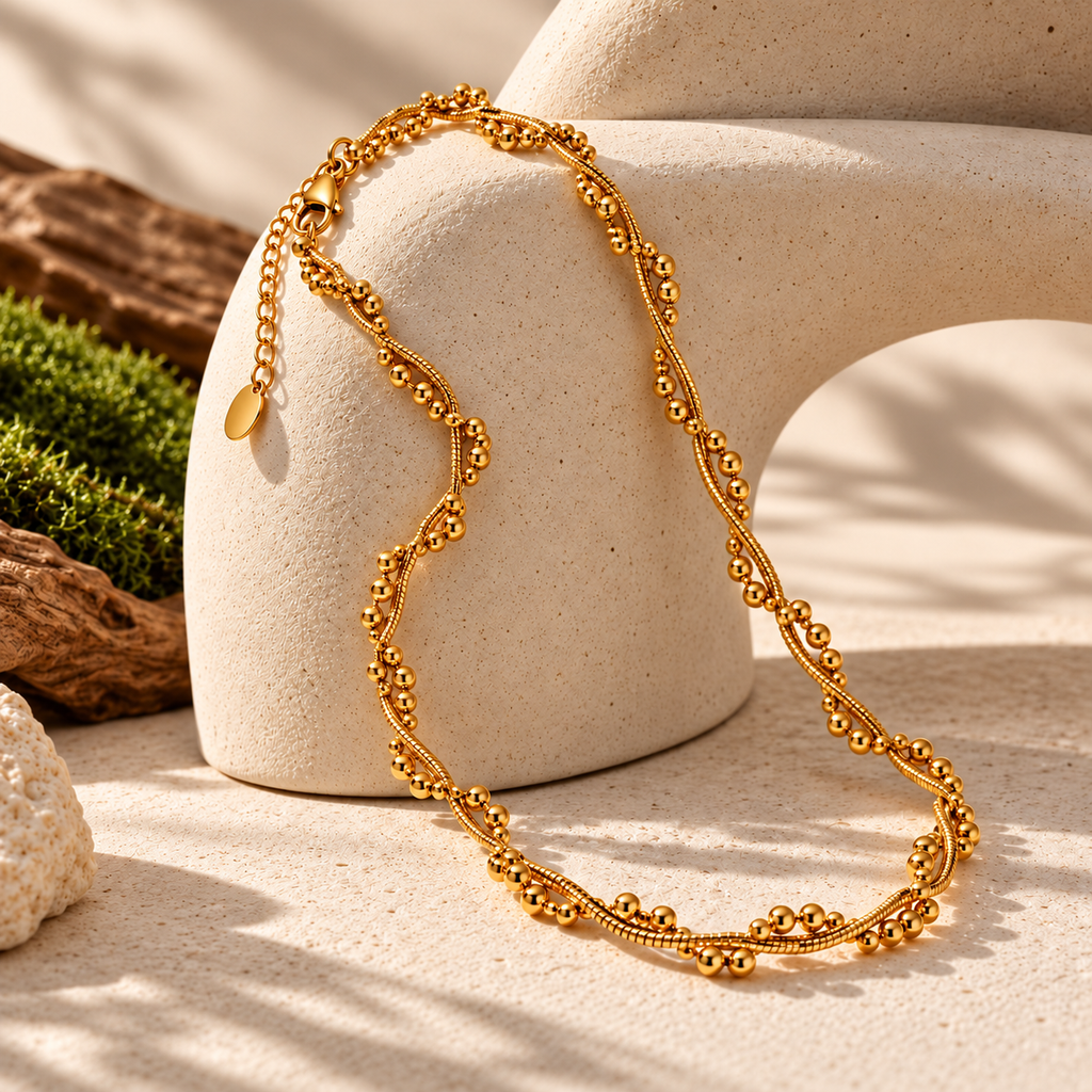 Colar BRISA dourado com corrente texturada sobre suporte de pedra clara numa composição editorial