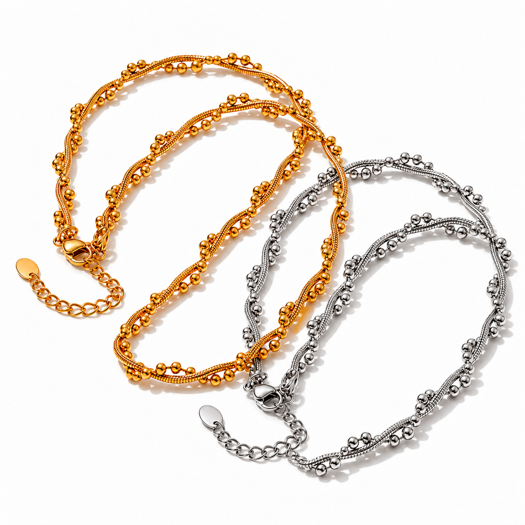 Colar BRISA em aço inoxidável nas variantes dourado e prateado, correntes texturadas com pequenos detalhes esféricos sobre fundo branco