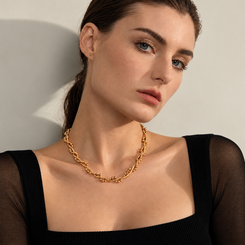 Modelo com Colar BRISA dourado em aço inoxidável, corrente texturada com contas decorativas sobre roupa preta