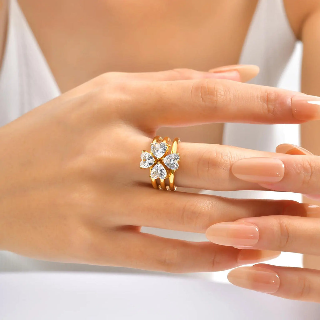 Anel AMARA em uso na mão feminina, com zircónias cúbicas em formato de coração e acabamento dourado.